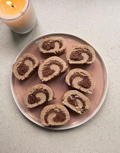 a plate full of cinnamon rolls next to a candle