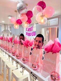 a table with pink bags and balloons hanging from the ceiling