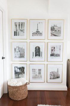 a white room with pictures on the wall and a basket in front of it next to a door