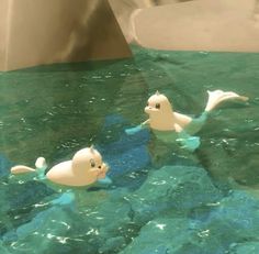 three plastic ducks floating on top of a body of water