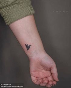 a small black bird tattoo on the wrist