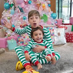 two children sitting in front of a christmas tree