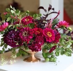 a vase filled with flowers sitting on top of a white table next to a couch