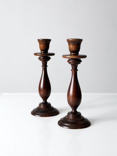 two wooden candlesticks sitting on top of a white table