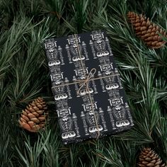 a black and white wrapping paper wrapped in twine on top of pine branches with cones