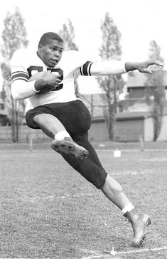 a black and white photo of a man kicking a soccer ball