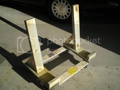 two wooden stands sitting in the middle of a parking lot next to a parked car