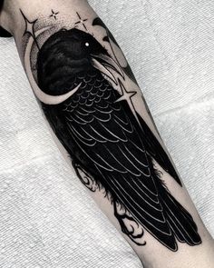 a black bird sitting on top of a person's arm with the moon behind it