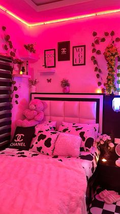 a bedroom decorated in pink and black with cow print bedding, pillows, and decor