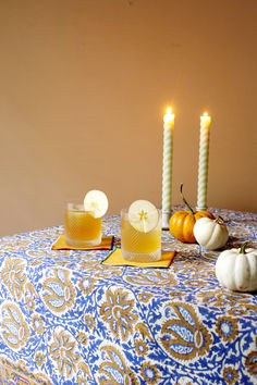 three candles are lit on a table with pumpkins