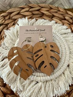 two wooden heart shaped earrings sitting on top of a woven basket next to a card