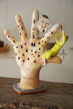 a ceramic sculpture of a hand holding a banana on top of a wooden table in a kitchen