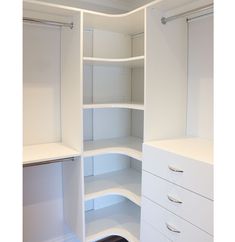 an empty closet with white shelves and drawers