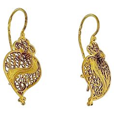 These Original Portuguese Viana's Heart Earrings are exquisite examples of traditional Portuguese jewelry craftsmanship. Crafted from luxurious 19kt yellow gold, these earrings feature the iconic Viana's Heart design, a symbol of love and devotion deeply rooted in Portuguese culture. The earrings showcase intricate filigree work, a hallmark of Portuguese jewelry, where delicate threads of gold are woven into intricate patterns. This meticulous craftsmanship results in a beautifully detailed and Portuguese Jewelry, Portuguese Culture, Heart Motif, Love Symbols, Intricate Patterns, Heart Earrings, Heart Design, Meaningful Gifts, Heart Shape