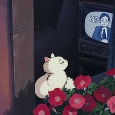 a white cat sitting in front of a flower pot with red flowers and a tv behind it