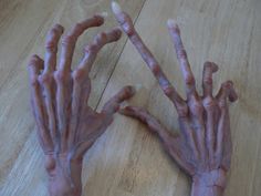 two hands that are covered in purple paint on a wooden table with one hand extended up