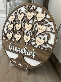 a family tree with names and hearts is shown on a wooden plaque that reads grandkids