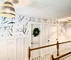 an entry way with white doors and wallpaper on the walls, next to a wooden banister