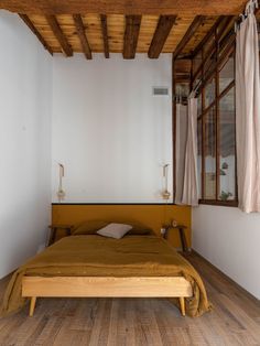 a bed sitting on top of a wooden floor next to a window in a bedroom