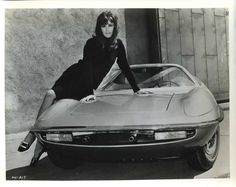 a woman leaning on the hood of a sports car