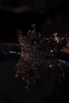 a crown sitting on top of a table next to a black surface with water droplets