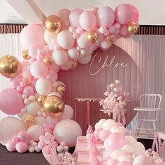 a table topped with lots of pink and gold balloons