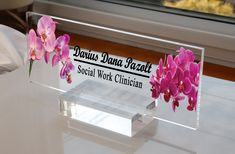 pink orchids are placed in front of a glass sign that says donuts dana fazzit social work clinic