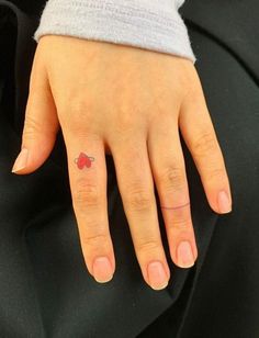 a woman's hand with a small red heart tattoo on it