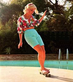 a woman riding a skateboard on top of a cement slab next to a swimming pool