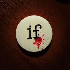 a white button with the word fi painted on it and blood splatters all over it