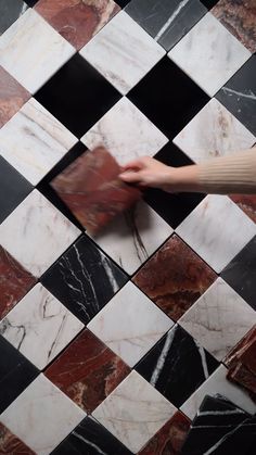 a black and white checkered tile floor with a person's hand reaching for it