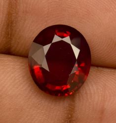 a close up of a person's hand holding a red diamond