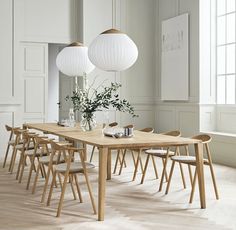 a dining room table with chairs and vases on it in front of white walls