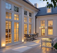 a large white house with lots of windows and lights on the side of it's front porch