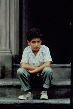 a young boy sitting on steps with his arms crossed