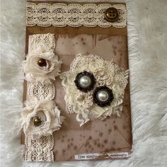 two pieces of fabric with lace and pearls on them sitting on a white furnishing