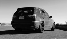 a black and white photo of a car parked on the side of the road with another car in the background