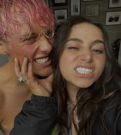 two women with pink hair and piercings are posing for the camera, one is smiling