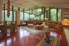 a living room filled with lots of furniture and large windows overlooking the trees in the distance