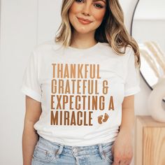 a woman wearing a t - shirt that says, thankful grateful and expecting a miracle