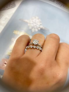 a close up of a person's hand with a ring on their finger and snowflakes in the background