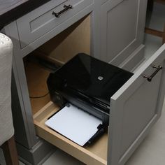 an open drawer in the middle of a kitchen counter with a laptop on it and papers inside