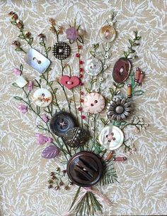 an arrangement of buttons and flowers on a white background with pink, green, purple, and brown accents