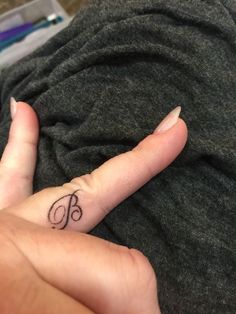 a woman's hand with a small tattoo on her left thumb and the letter b in the middle