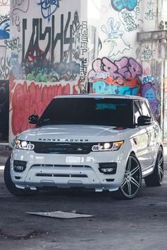 a white range rover parked in front of graffiti covered walls