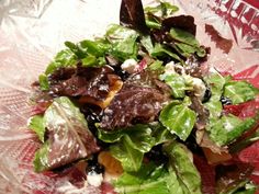 a close up of a salad in a glass bowl on a table with plastic wrapper