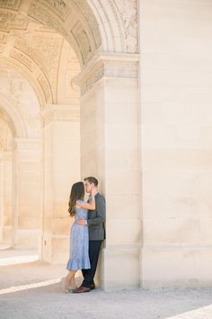 a man and woman standing next to each other in front of a building with arches