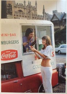 a woman in white pants standing next to a red and white food truck with coca cola on it