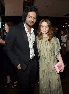 a man and woman standing next to each other at a formal event, posing for the camera