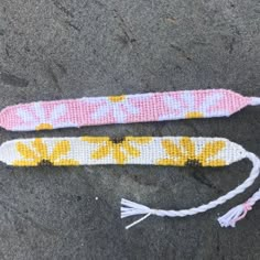 two cross - stitch bracelets are laying on the ground next to each other and one has a tassel